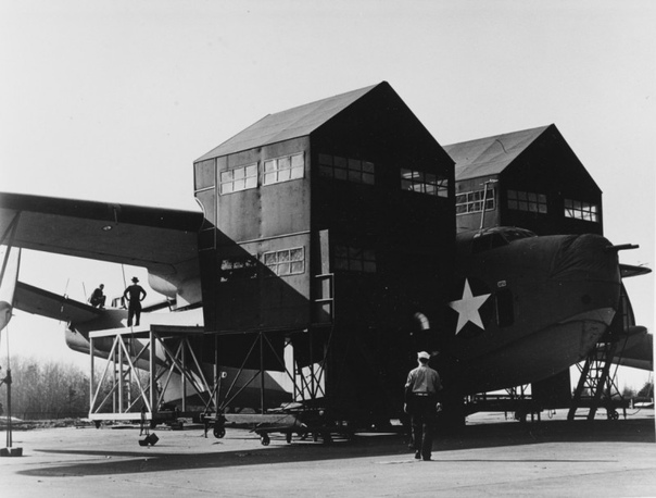 Станное сооружение на гидросамолёте PBM-3D на авиазаводе Glenn L Martin в городе Балтимор штата Мэриленд, 1943 год.Двигатели самолёта накрыты специальным мобильным укрытием, позволяющим техникам